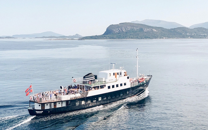 Fjord boat cruising near Ålesund with passengers on deck.