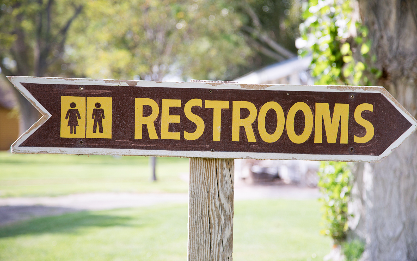 Outdoor restroom sign with directional arrow.