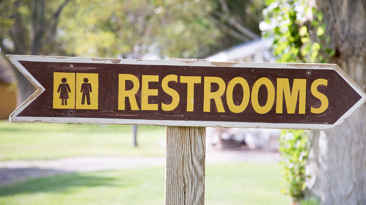 Outdoor restroom sign with directional arrow.