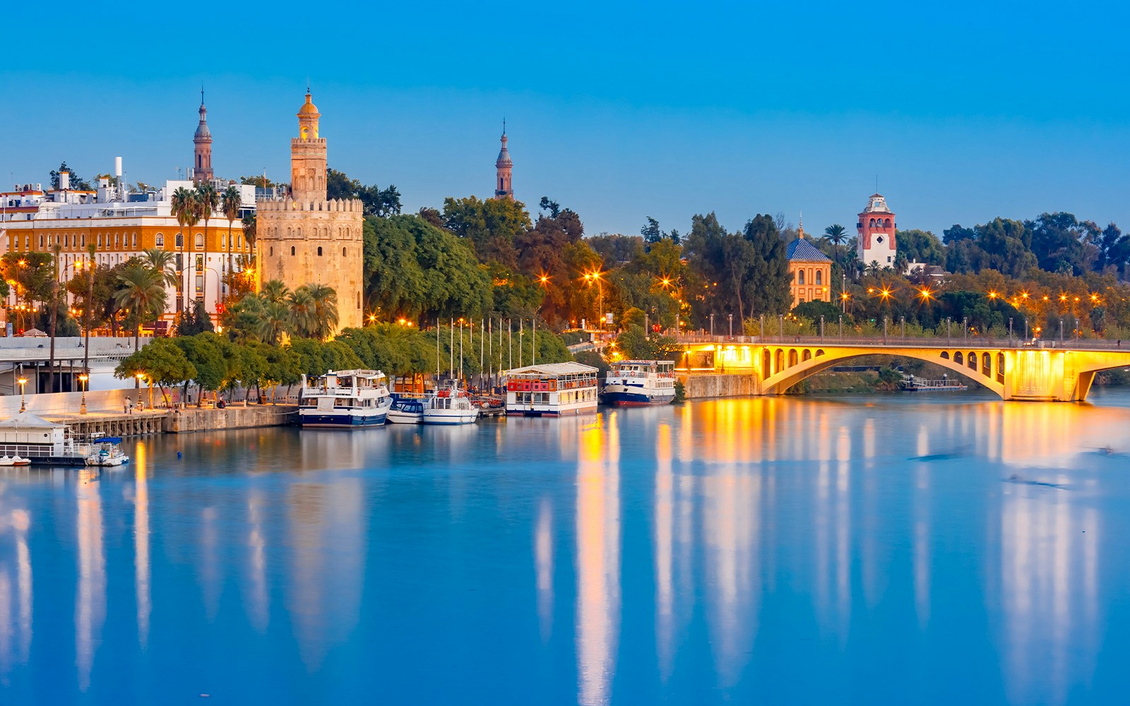 Golden Tower or Torre del Oro and bridge Puente San Telmo during evening blue hour, Seville