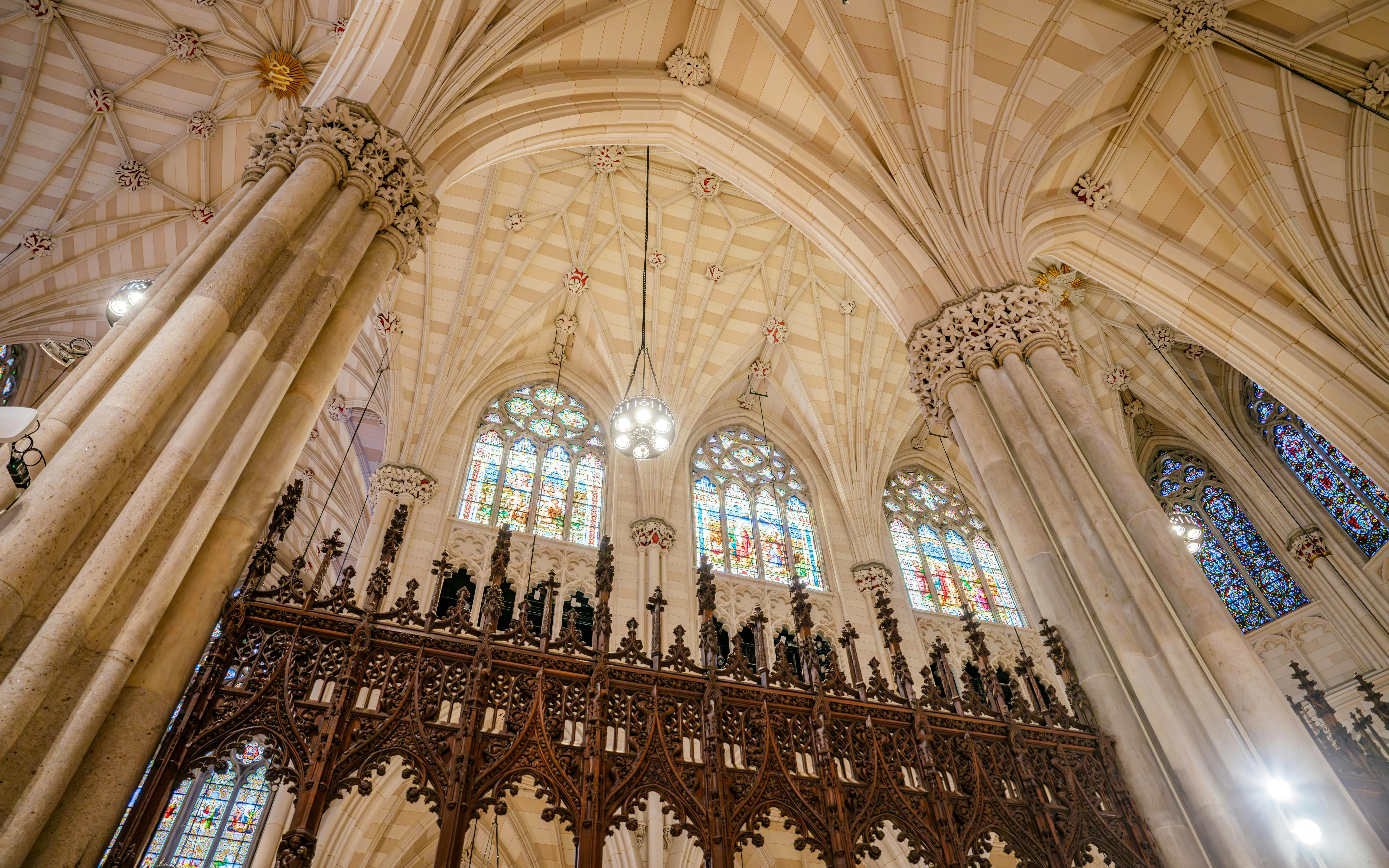 Ribbed vaulted ceiling, detailed choir screen, and stained glass windows in St. Patrick's Cathedral, NYC.