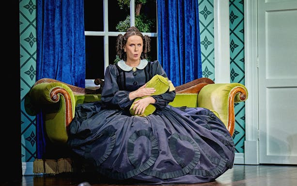 Stage scene from Oh, Mary Westend show with actor in period costume on a vintage sofa.