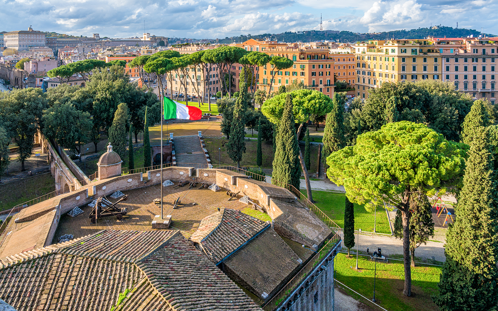 Panoramic view from Castel Sant'Angelo terrace overlooking Rome with Italian flag.