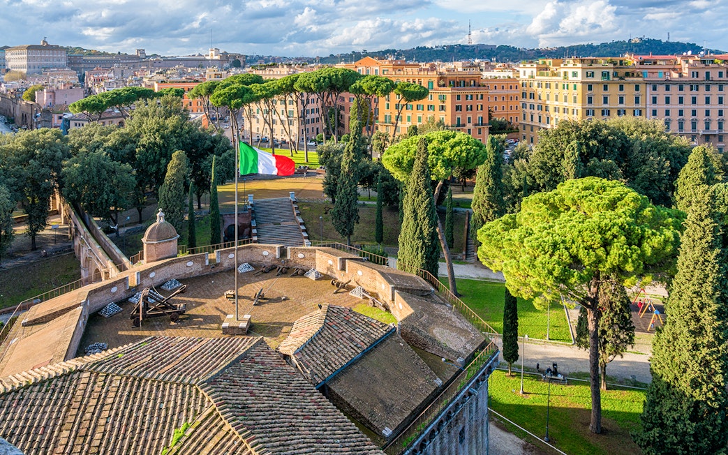 Panoramic view from Castel Sant'Angelo terrace overlooking Rome with Italian flag.