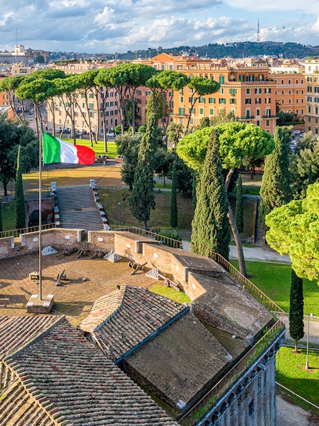 Panoramic view from Castel Sant'Angelo terrace overlooking Rome with Italian flag.