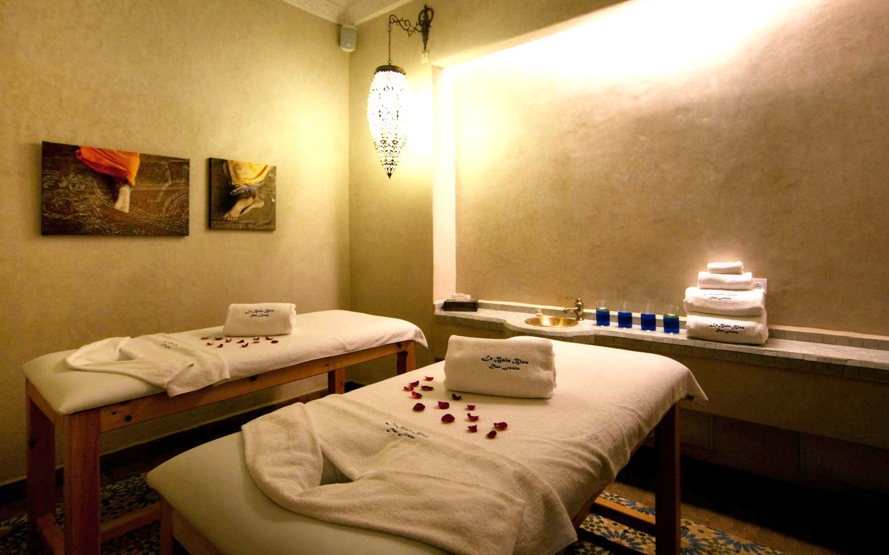 Massage tables with towels and rose petals at Le Bain Bleu Hammam & Spa, Marrakesh.