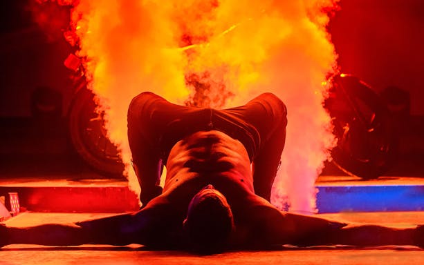 Performer on stage with smoke effects during Chippendales act.
