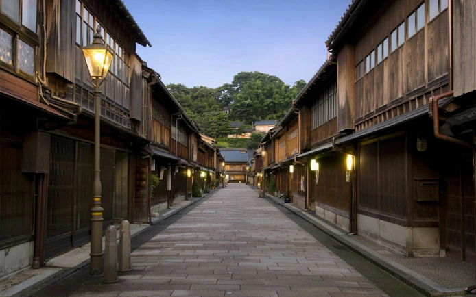 Traditional wooden street in Kanazawa, Japan, illuminated by lanterns at dusk.