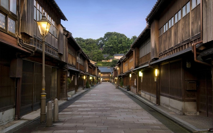 Traditional wooden street in Kanazawa, Japan, illuminated by lanterns at dusk.