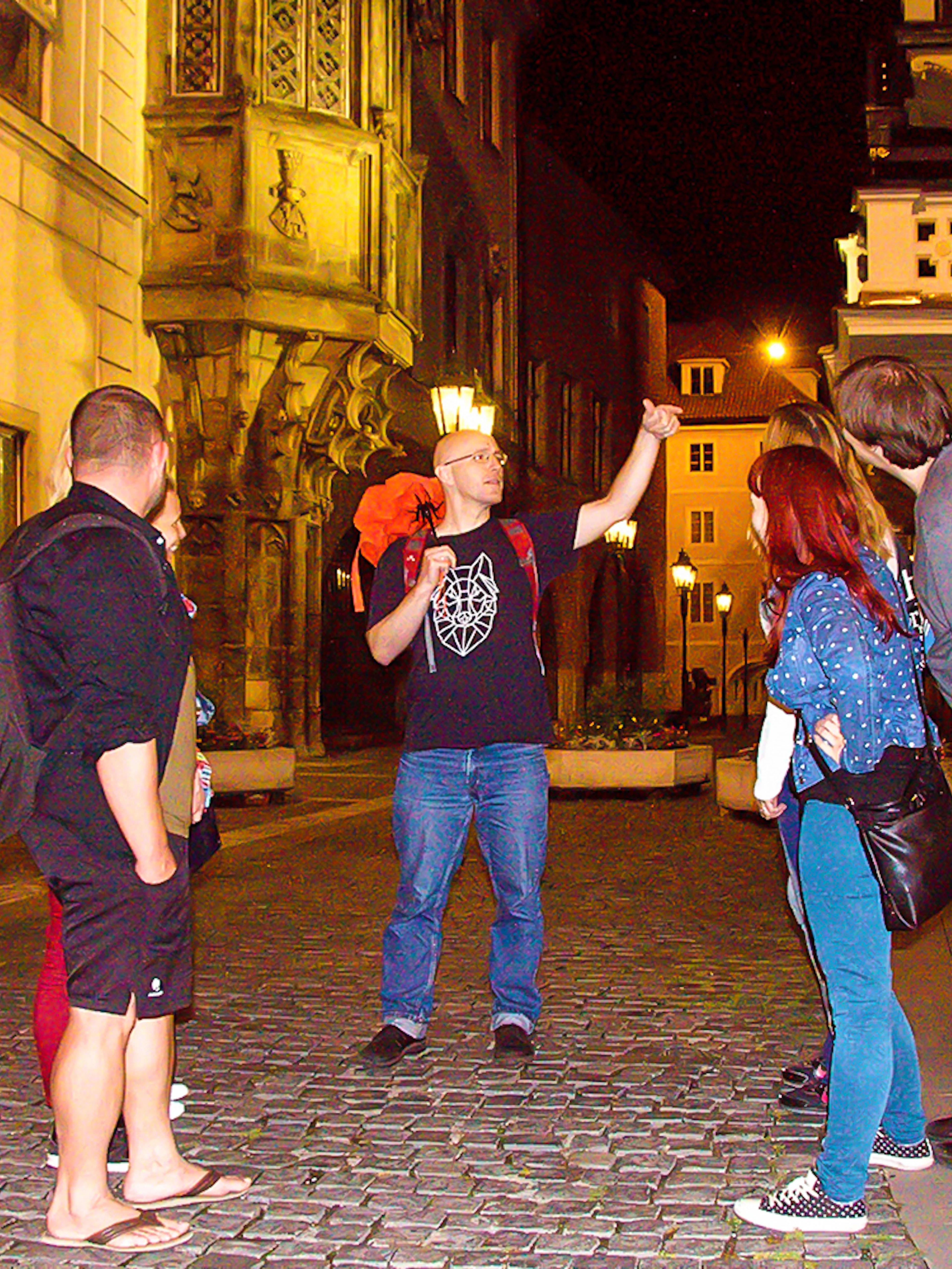 Tour guide explaining to tourists during Ghosts and Legends of Prague tour at night.
