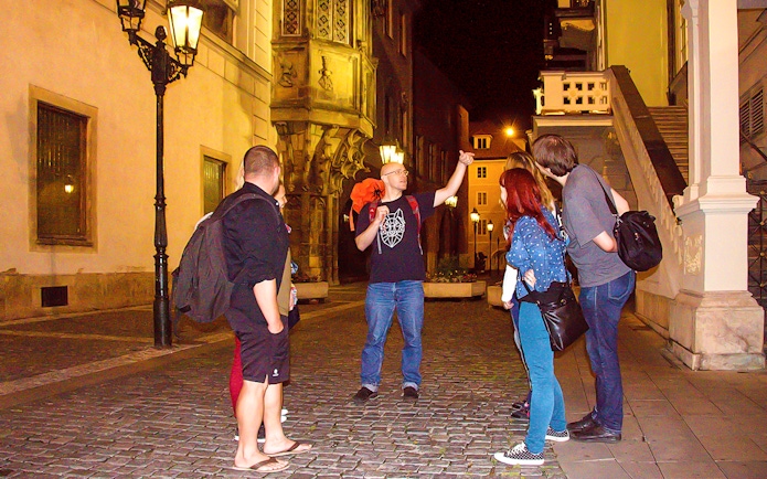 Tour guide explaining to tourists during Ghosts and Legends of Prague tour at night.