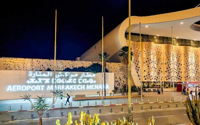Marrakech Menara Airport entrance at night, featuring modern architecture and illuminated signage.