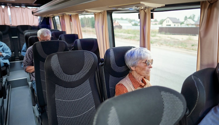 old woman enjoying views from a window seat inside a bus to segovia