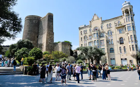 Tour group gathered near Maiden Tower in Baku with historic architecture in the background.