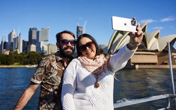 Couple taking a selfie on a Sydney Harbour Cruise with the Opera House in the background.