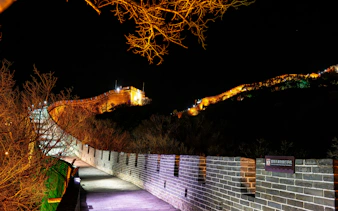 Badaling Great Wall illuminated at night, Beijing, with lit pathway and surrounding trees.