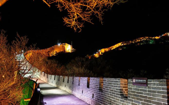 Badaling Great Wall illuminated at night, Beijing, with lit pathway and surrounding trees.