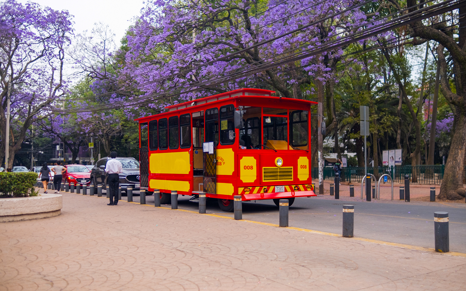 Tram passing through vibrant streets of Mexico City with historic buildings in the background.