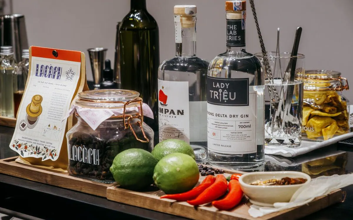 Vietnamese coffee beans, gin bottles, limes, and chili peppers arranged for a coffee-themed cocktail experience.