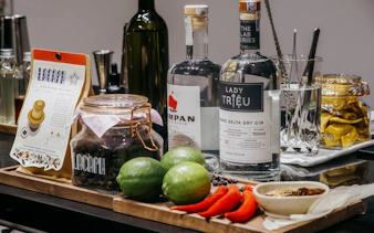 Vietnamese coffee beans, gin bottles, limes, and chili peppers arranged for a coffee-themed cocktail experience.