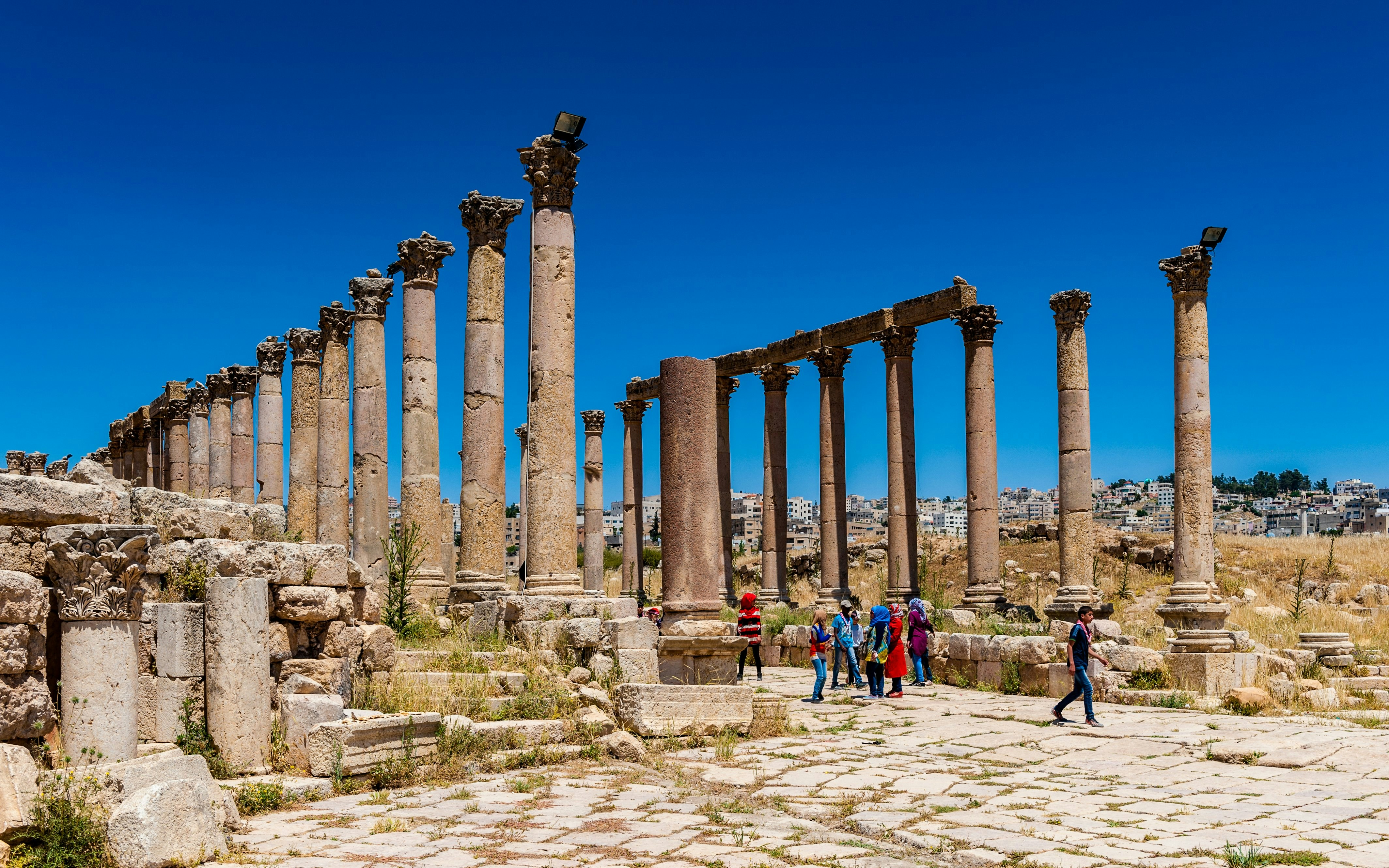 Columns of the Cardo Maximus in Jerash, Jordan with tourists exploring the ancient site.