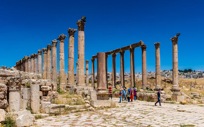 Columns of the Cardo Maximus in Jerash, Jordan with tourists exploring the ancient site.