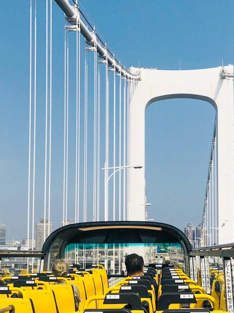 Open-top bus crossing Rainbow Bridge in Tokyo.