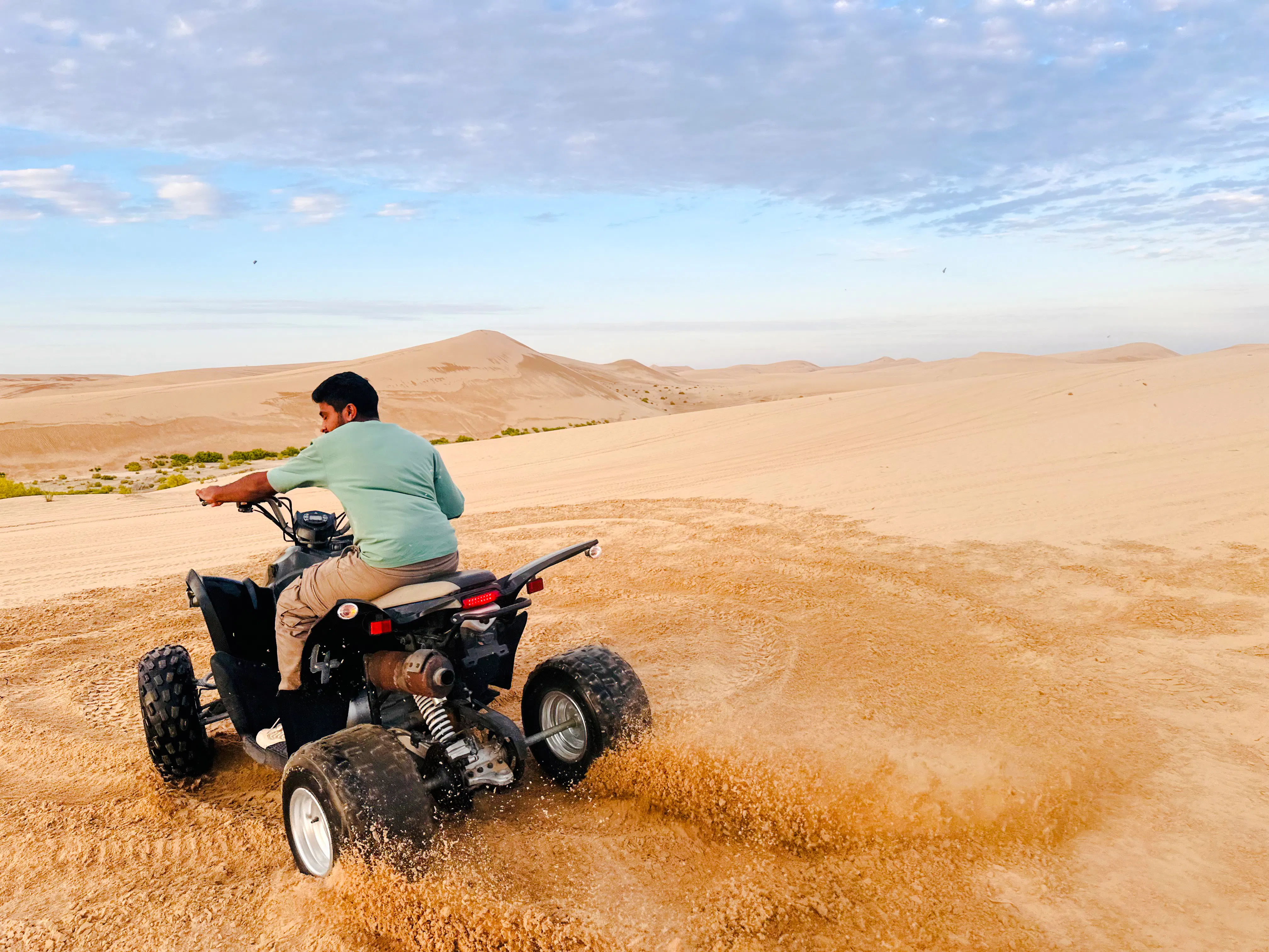 Quad biking on sand dunes during Abu Dhabi morning desert safari.
