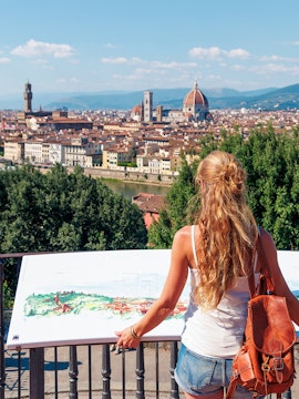 Woman viewing Florence skyline with Duomo and Palazzo Vecchio in the distance.