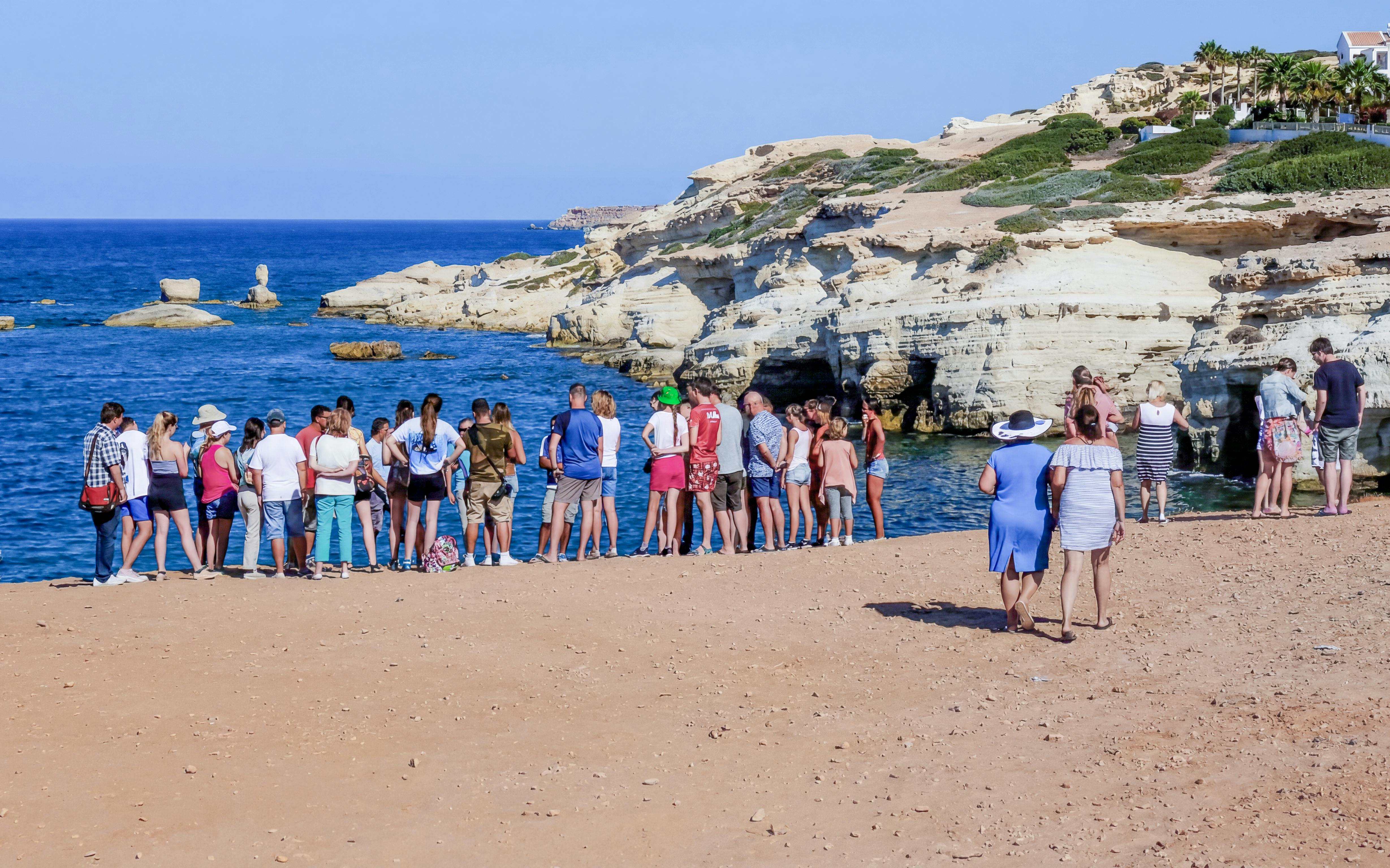 Tour group exploring sea caves along the coast near Paphos, Cyprus.