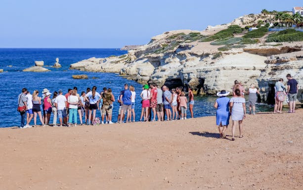 Tour group exploring sea caves along the coast near Paphos, Cyprus.