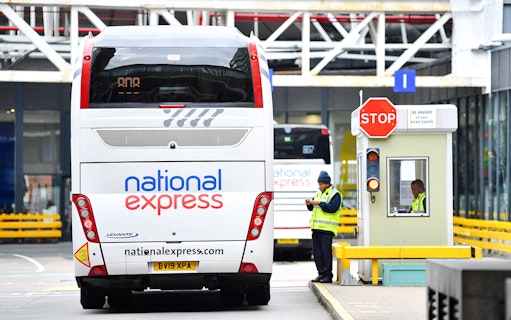 Bus at London Victoria Station with staff managing transfers.