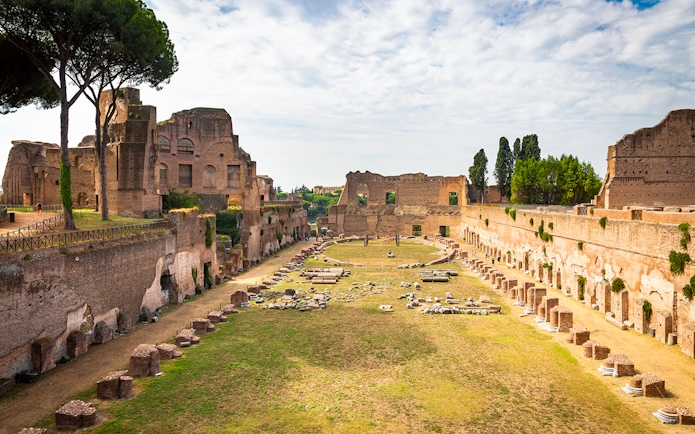 Roman Forum ruins with ancient structures and greenery, view from Palatine Hill, Rome.