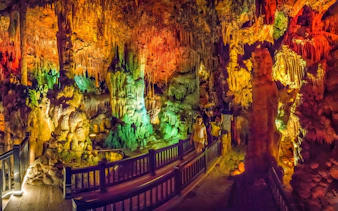 Colorful stalactites and stalagmites in Dim Cave, Alanya, with visitors exploring the illuminated path.