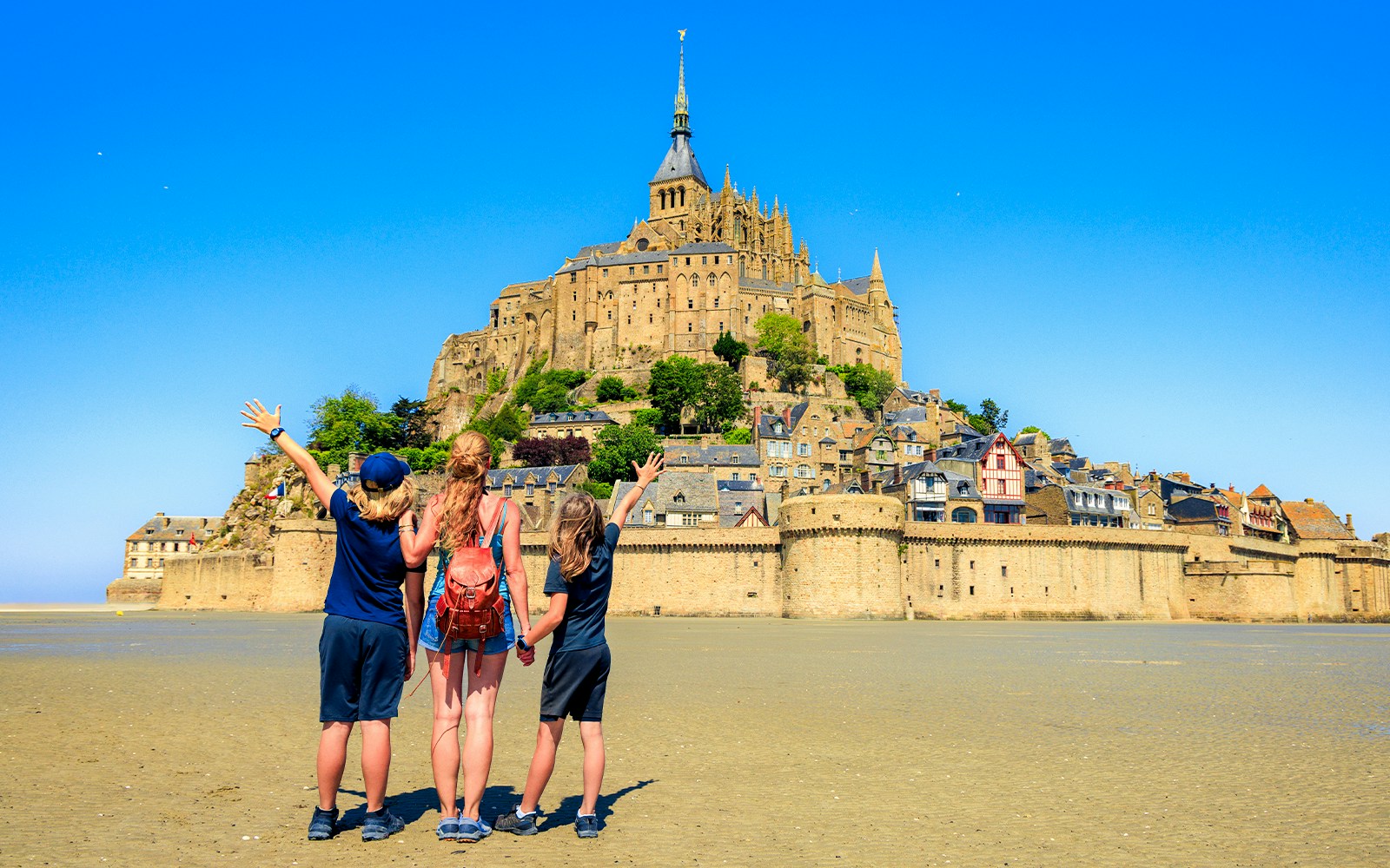 Mont Saint-Michel abbey view with tourists exploring the historic island, Normandy, France.