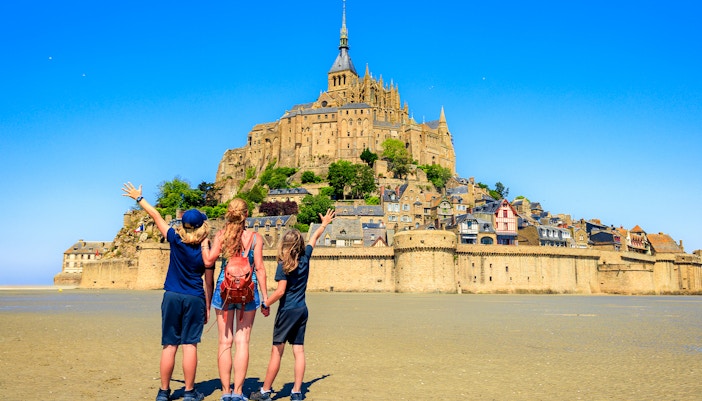Mont Saint-Michel abbey view with tourists exploring the historic island, Normandy, France.