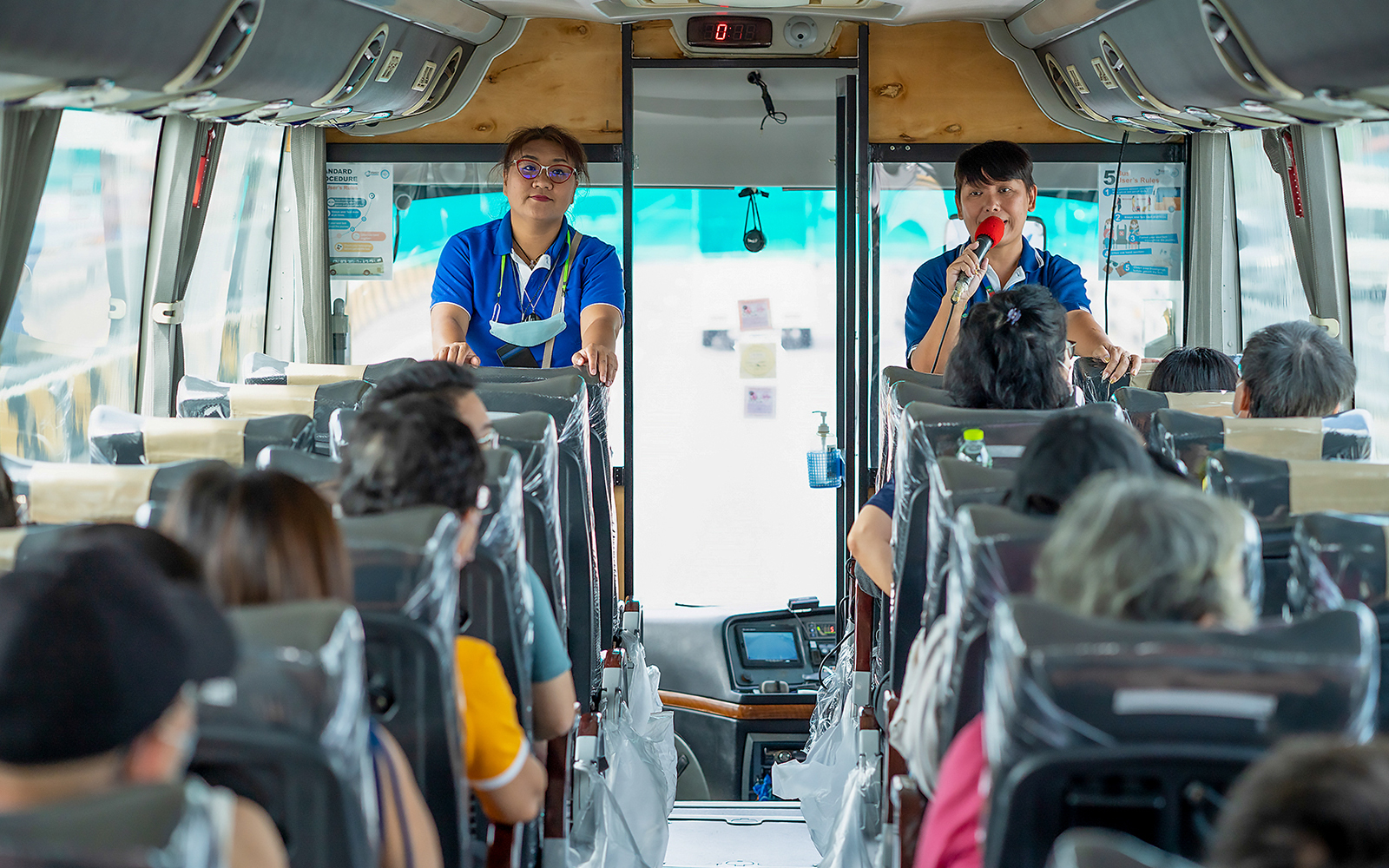 Tour guide speaking to passengers on a bus during Bangkok tour.