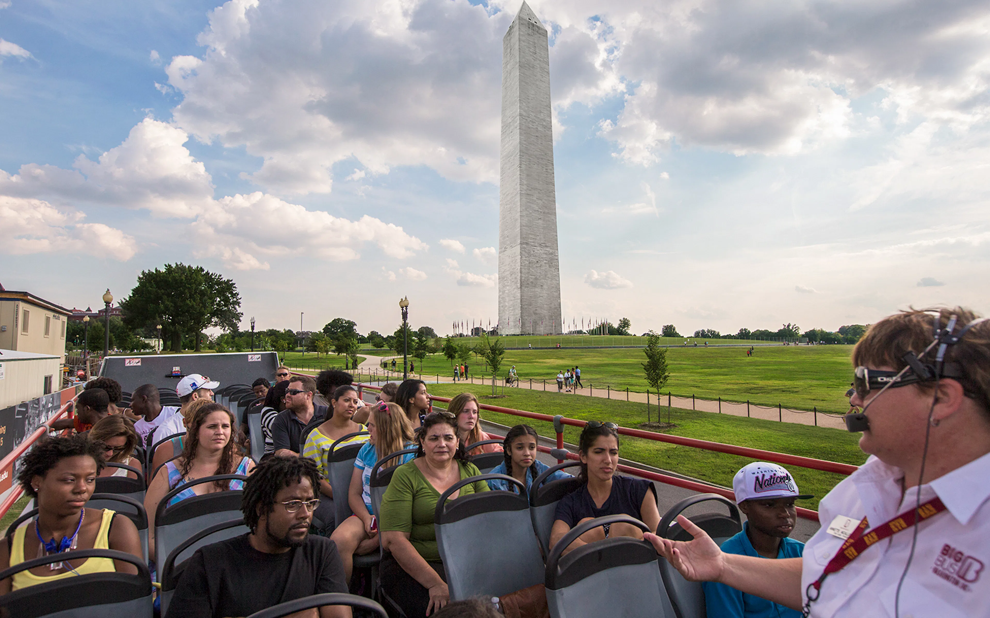 Tourists on a Big Bus Tour in Washington, D.C., with the Washington Monument in the background.