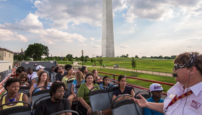 Tourists on a Big Bus Tour in Washington, D.C., with the Washington Monument in the background.
