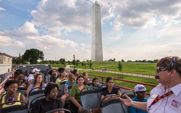 Tourists on a Big Bus Tour in Washington, D.C., with the Washington Monument in the background.