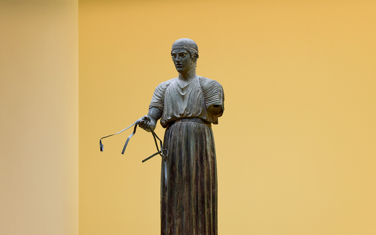 Sculpture of a charioteer holding reins inside Delphi Museum.