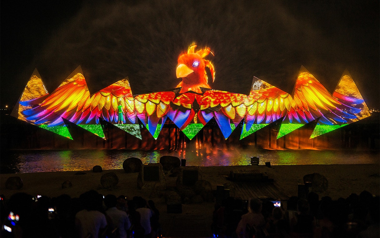 Wings of Time night show with colorful lights and bird projection at Sentosa Island.