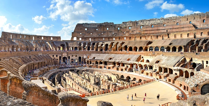Colosseum Arena interior with tourists exploring ancient Roman architecture in Rome, Italy.