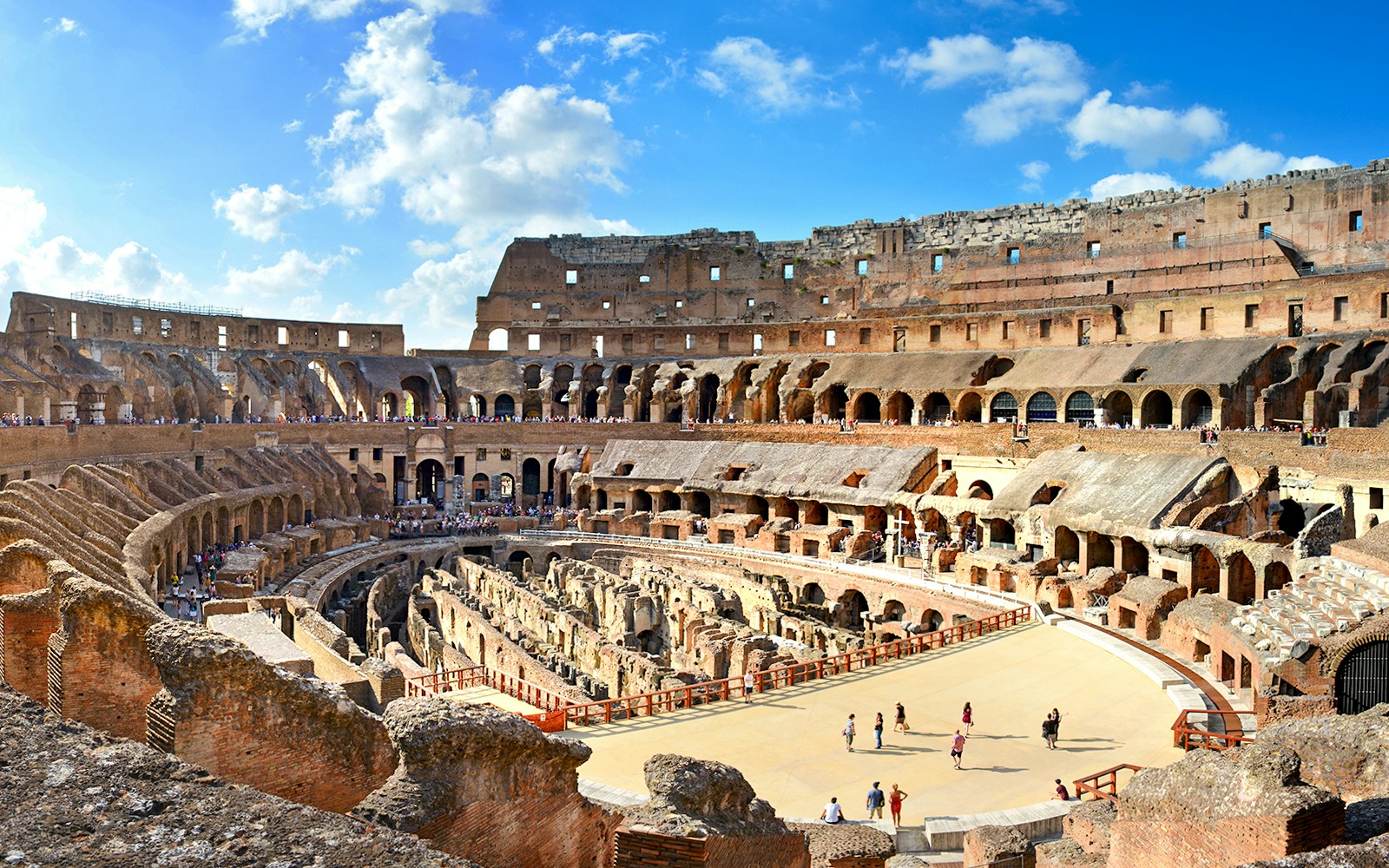 Colosseum Arena interior with tourists exploring ancient Roman architecture in Rome, Italy.