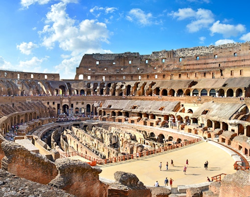 Colosseum Arena interior with tourists exploring ancient Roman architecture in Rome, Italy.