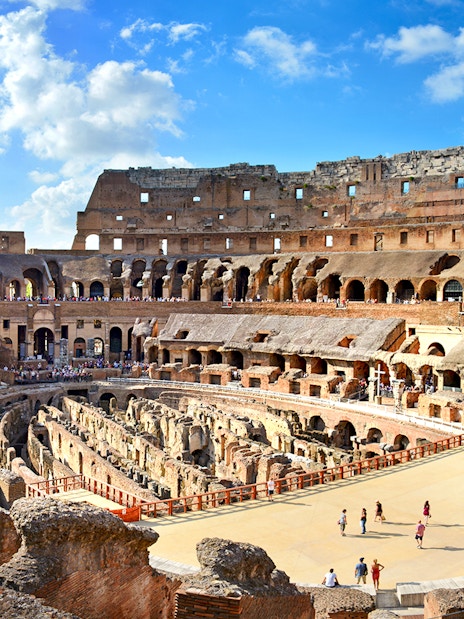 Colosseum Arena interior with tourists exploring ancient Roman architecture in Rome, Italy.