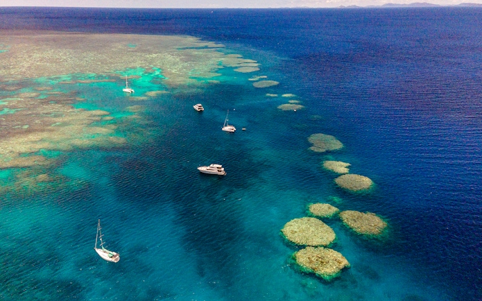 Small boats sailing near coral reefs in the Great Barrier Reef, Cairns.