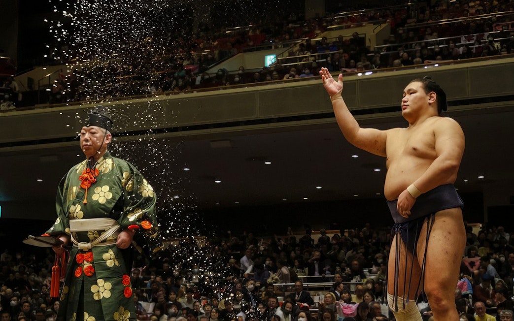 Sumo wrestler throwing salt during a traditional ceremony in Japan.