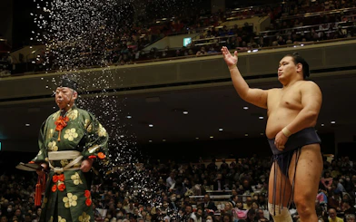 Sumo wrestler throwing salt during a traditional ceremony in Japan.