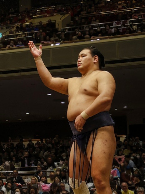 Sumo wrestler throwing salt during a traditional ceremony in Japan.